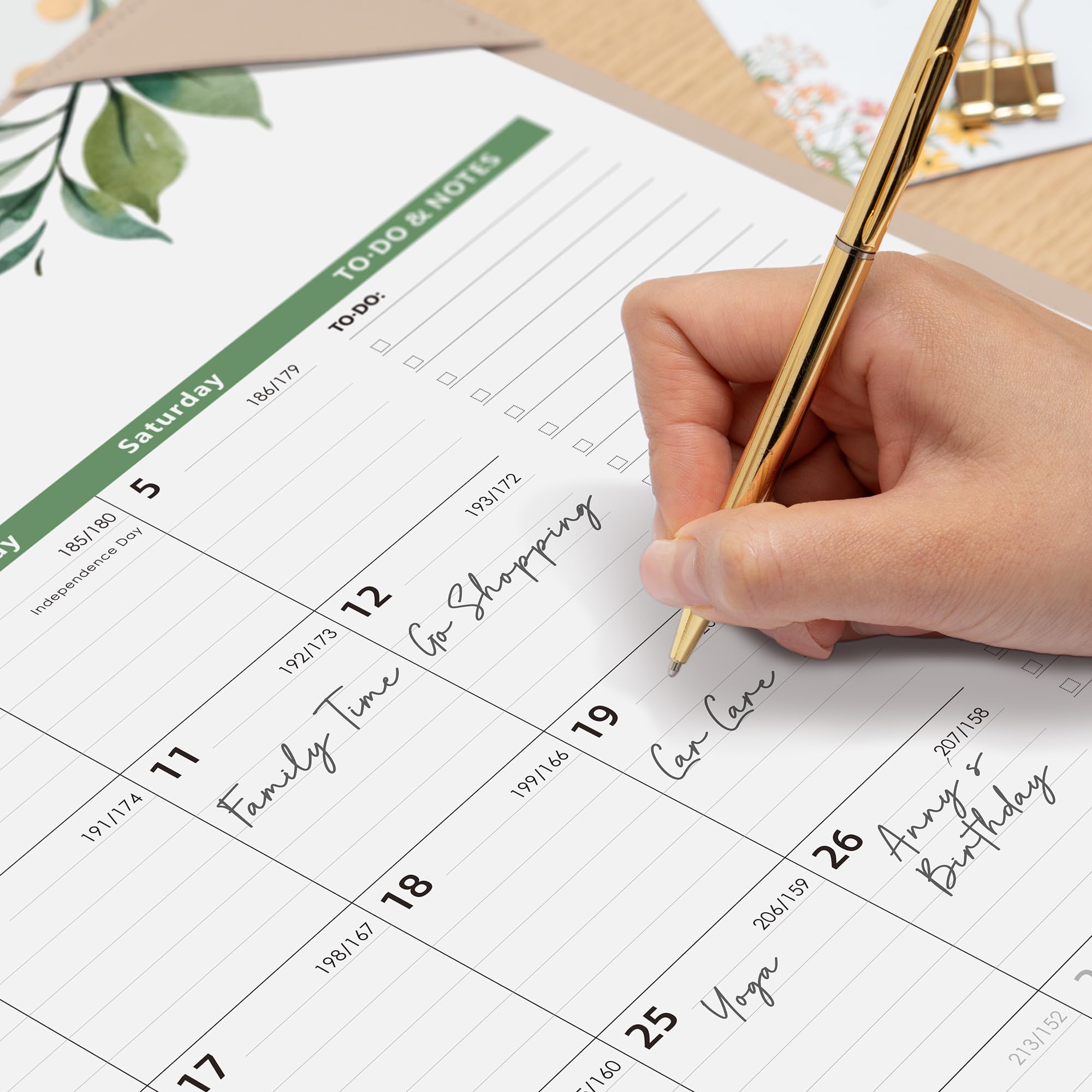 Hand holding a pen over a planner with handwritten notes