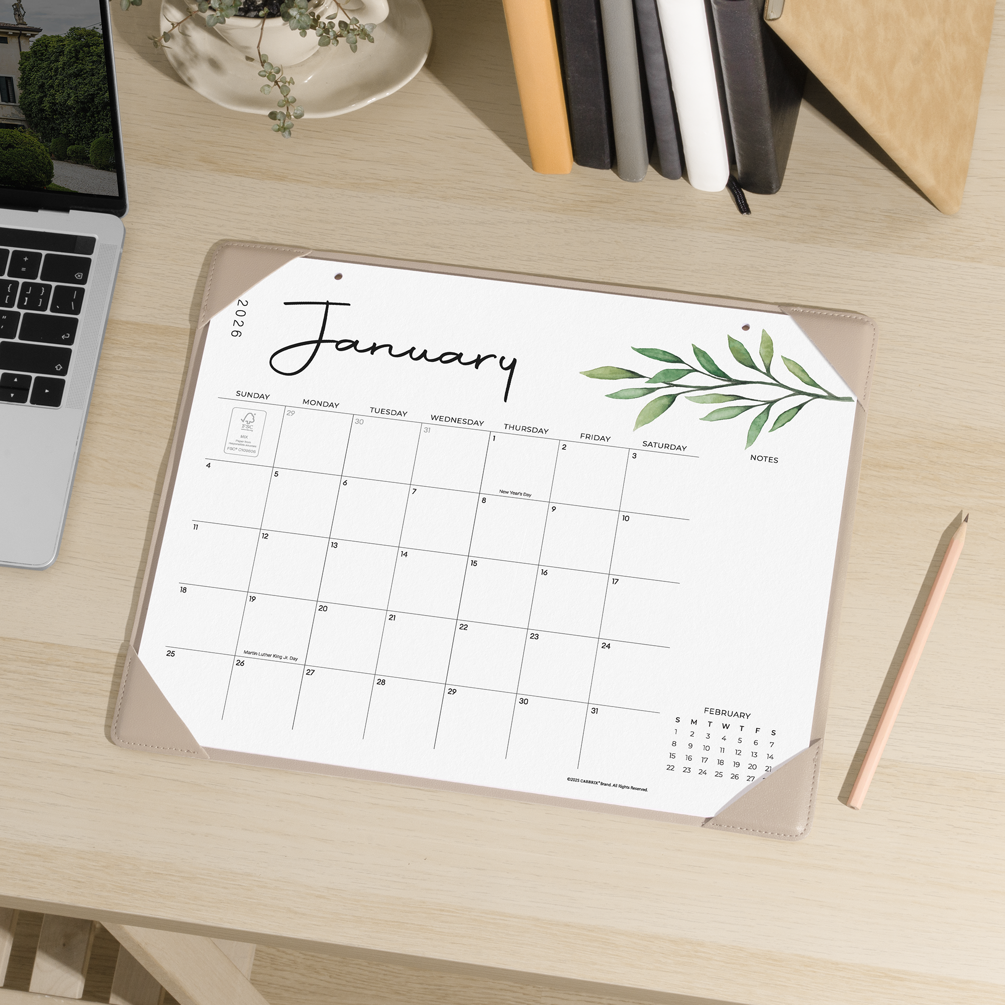 Calendar on a desk with a pen and laptop