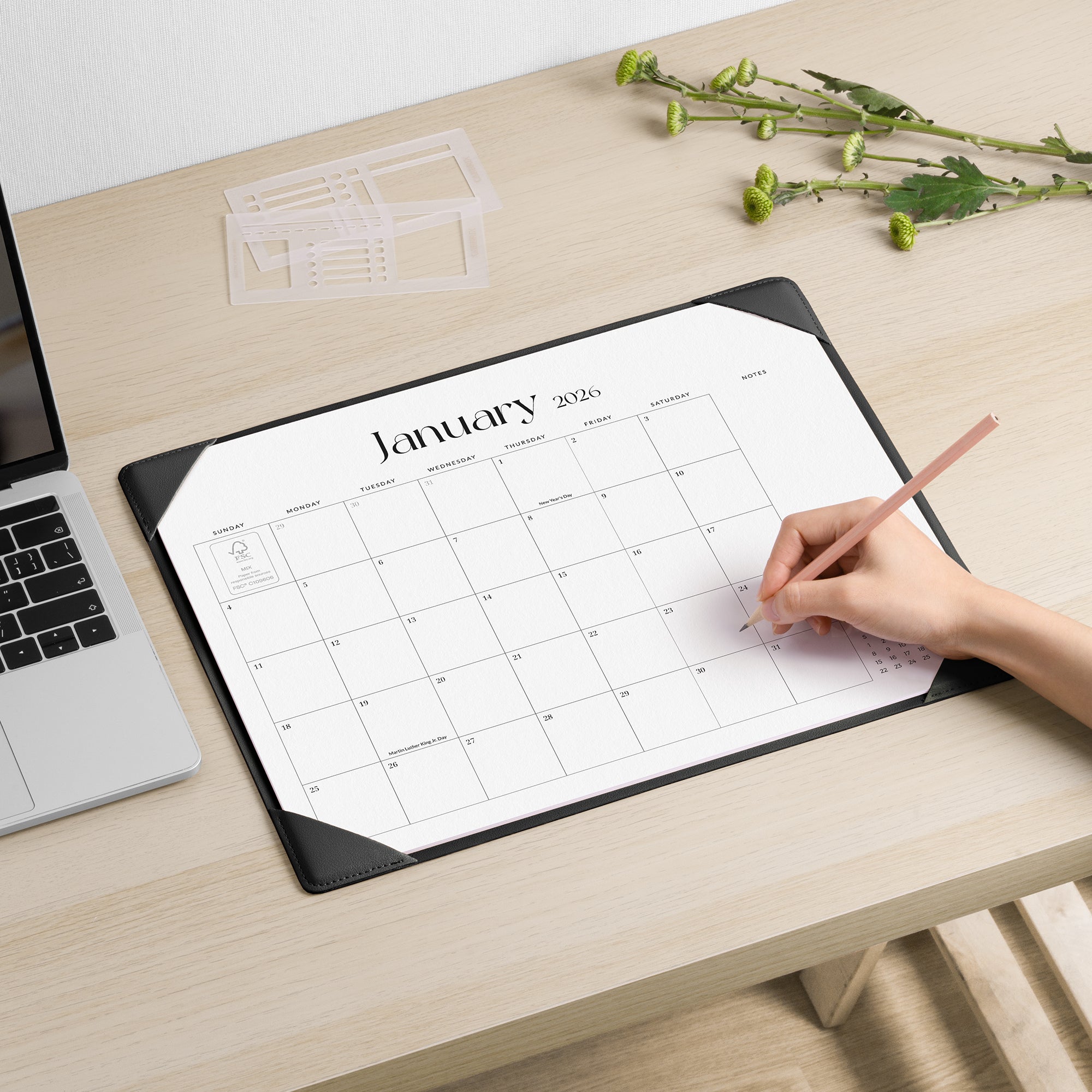Person using a desk pad with January 2020 calendar on a desk.