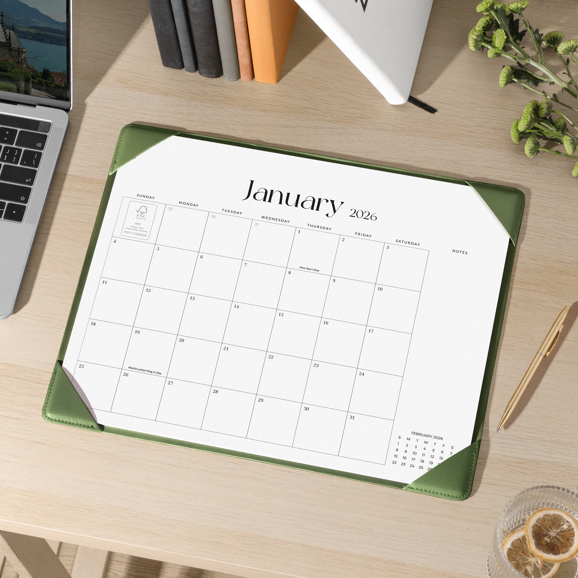 Calendar for January 2026 on a desk with a laptop and stationery items.