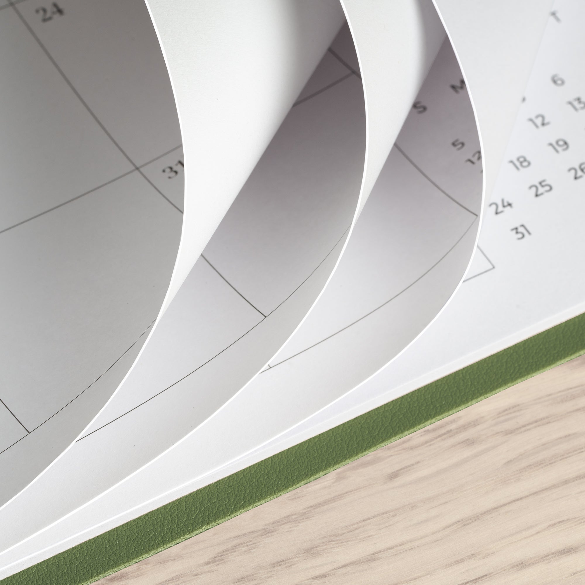 Close-up of a spiral-bound notebook with pages curling outwards on a wooden surface.