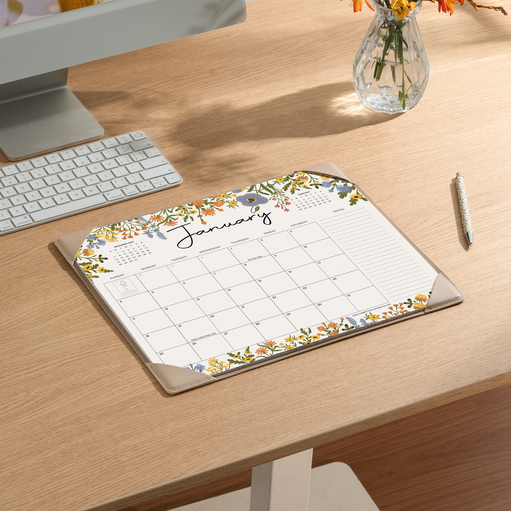 Calendar on a desk with a computer and flowers in the background