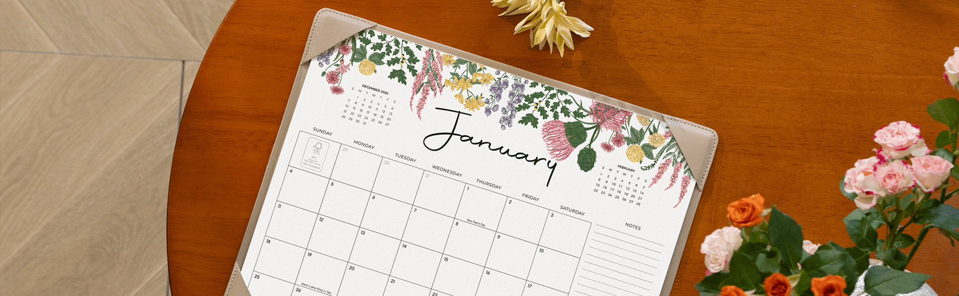 Calendar with floral design on a wooden table with flowers
