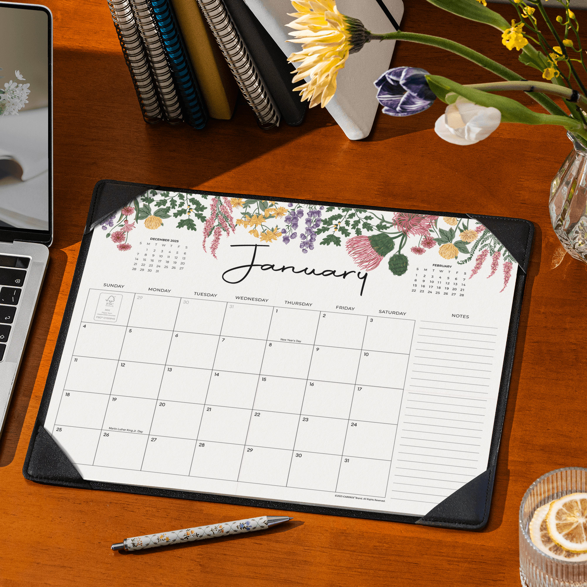 Floral January calendar on a desk with a laptop and flowers.