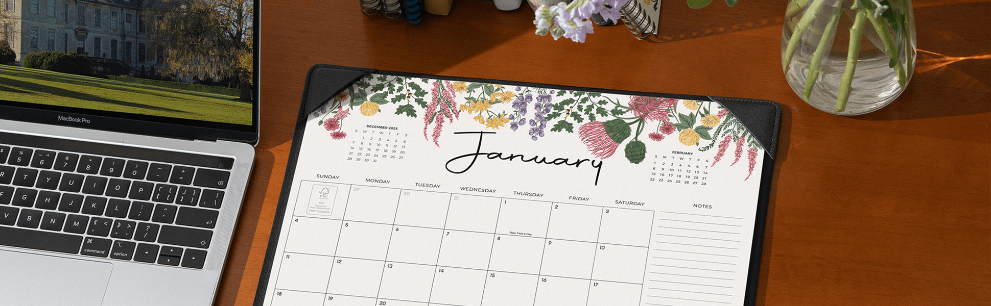 Calendar with floral design on a desk next to a laptop