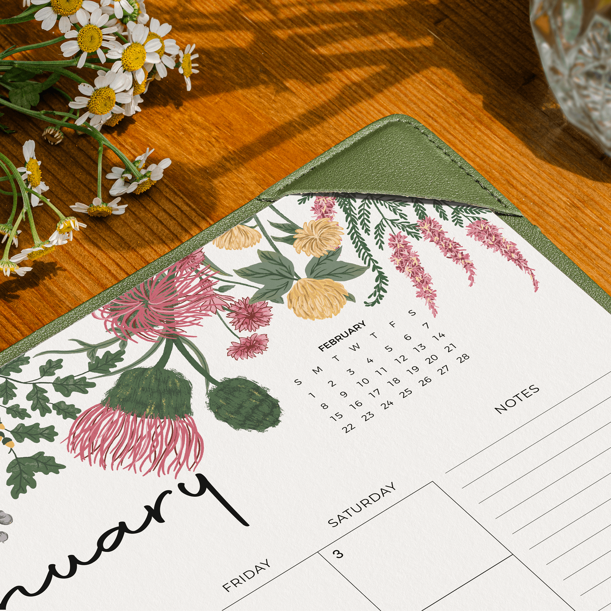 Floral-patterned calendar on a wooden surface with flowers.