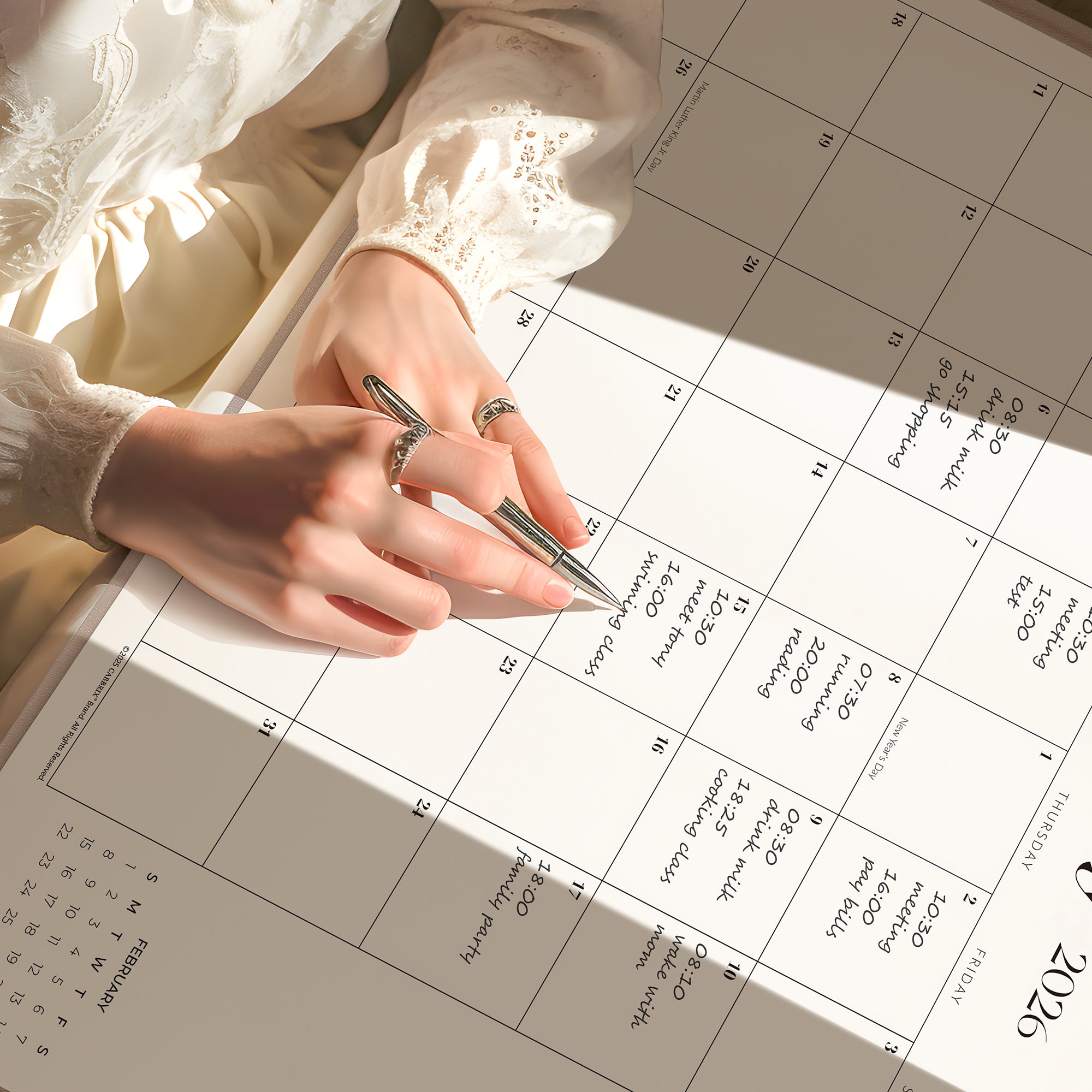 Person holding a pen over a calendar with a soft focus background