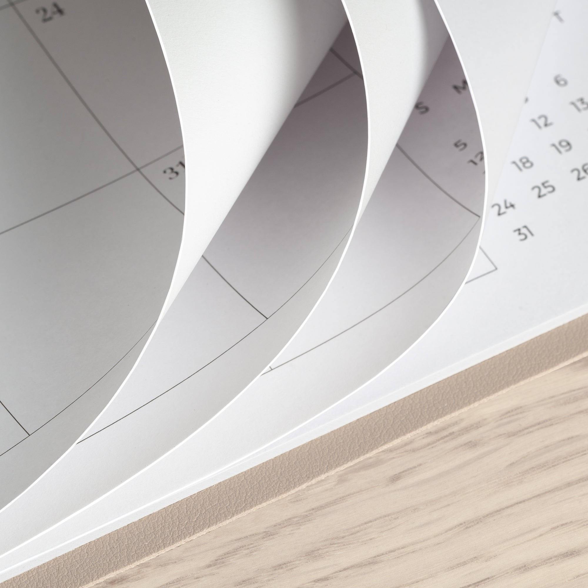 Close-up of a spiral-bound notebook with pages curling outwards on a wooden surface.