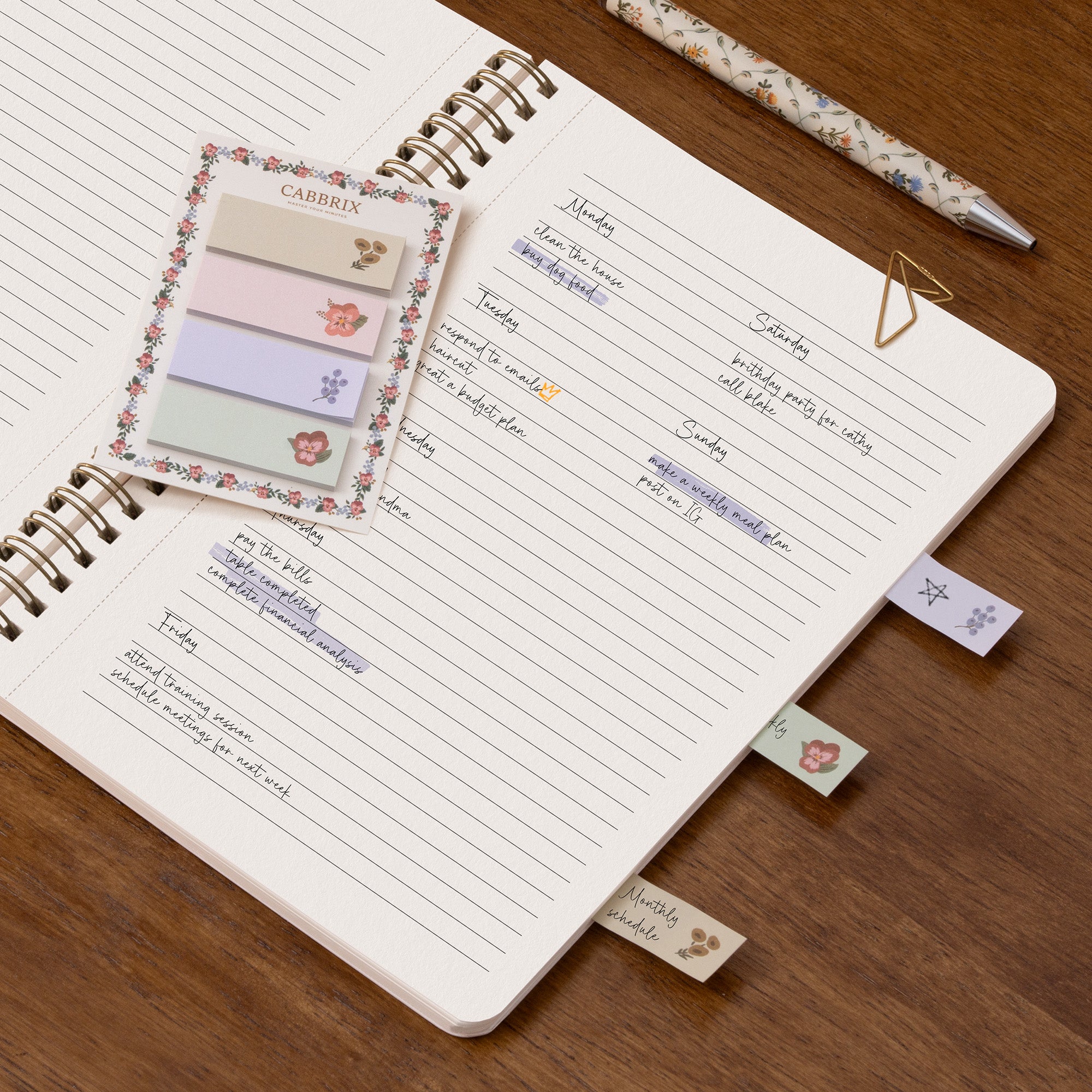 Open notebook with floral sticky notes and flags on a wooden surface