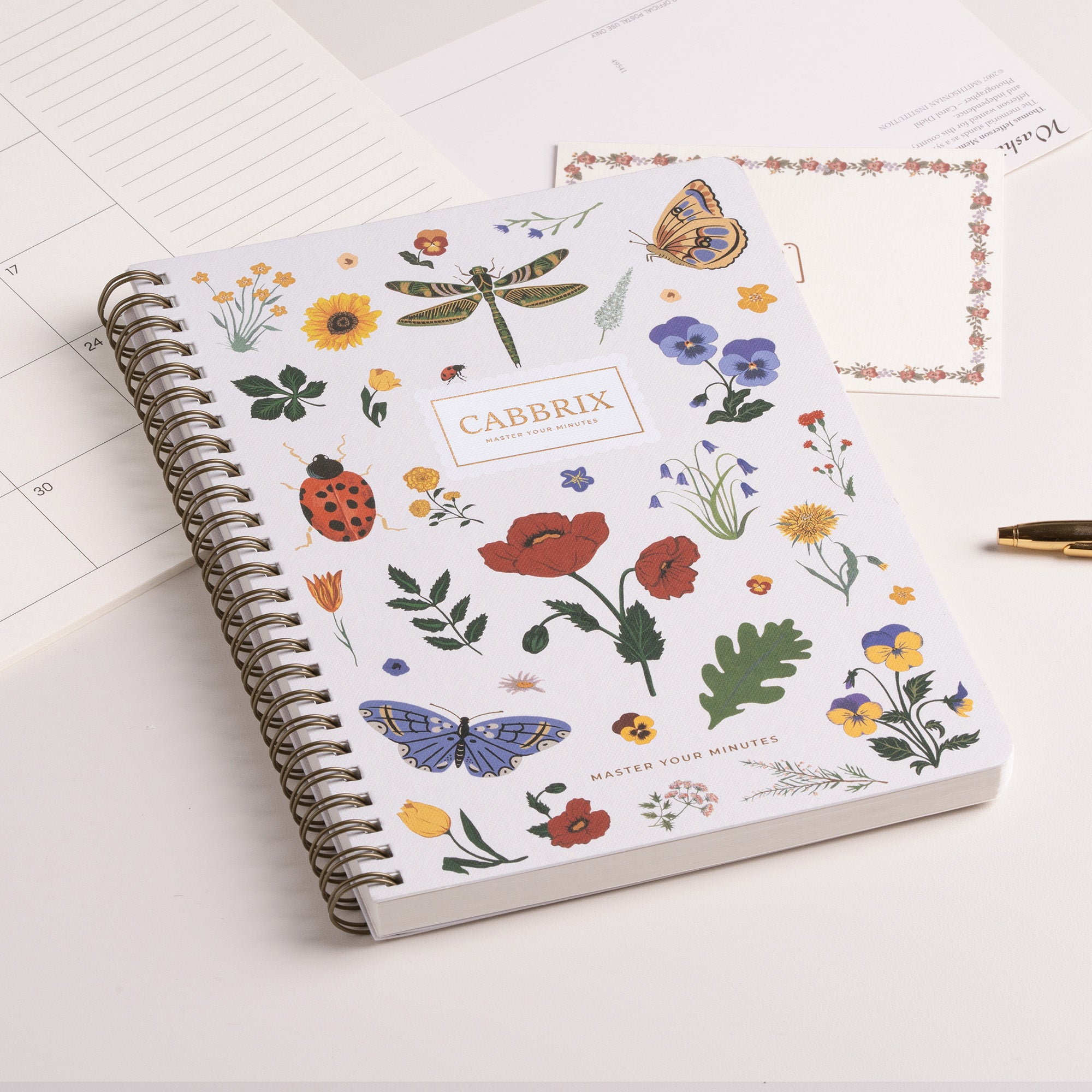 Notebook with floral and insect design on a white surface