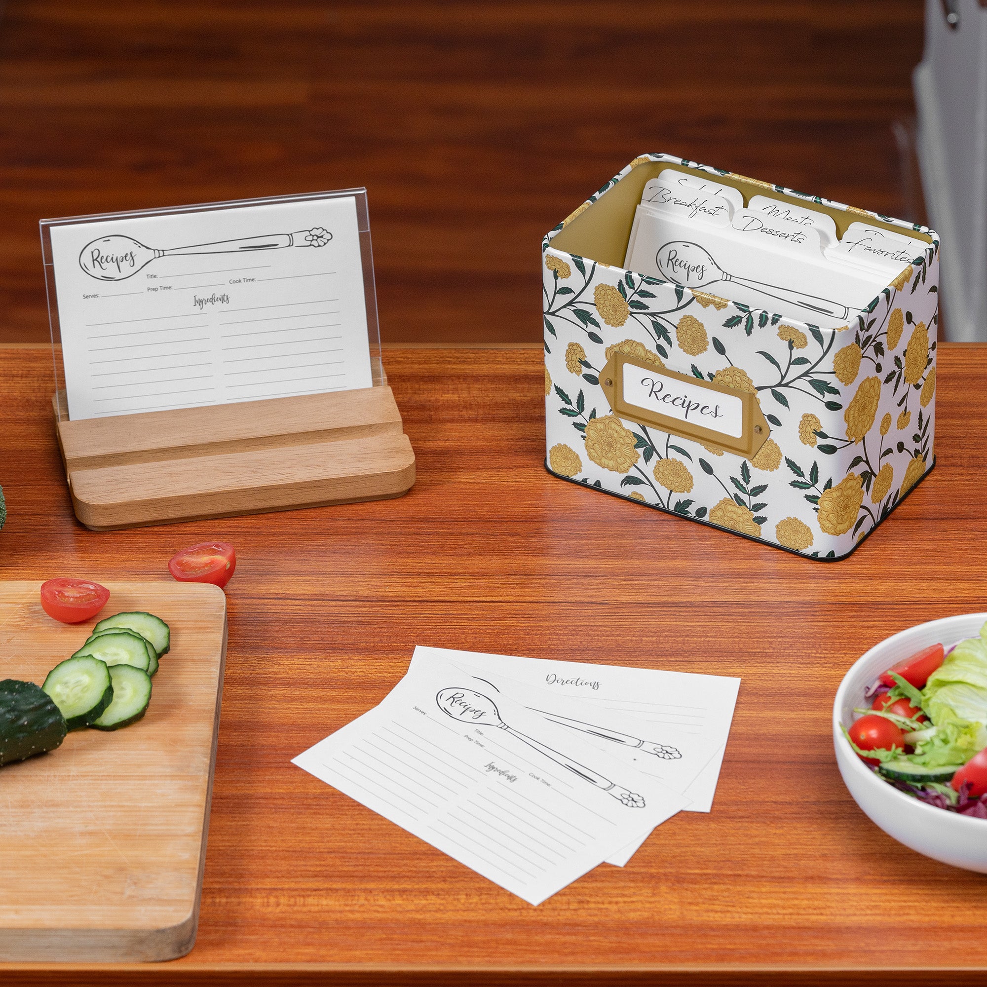 Recipe card holder with cards on a wooden table with a salad and vegetables.