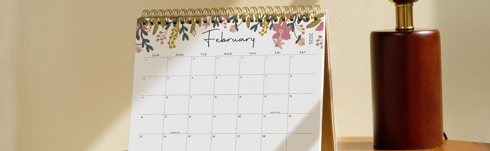 Calendar with floral design on a table next to a lamp