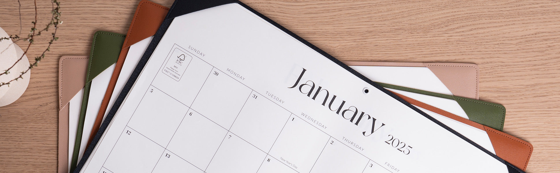 January 2023 calendar on a wooden surface with stationery items.