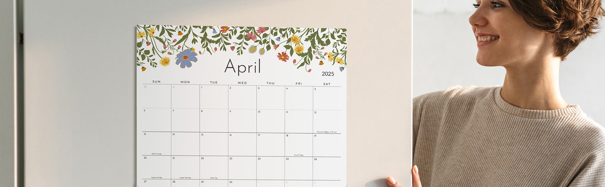 Woman holding a calendar with floral design on a white wall