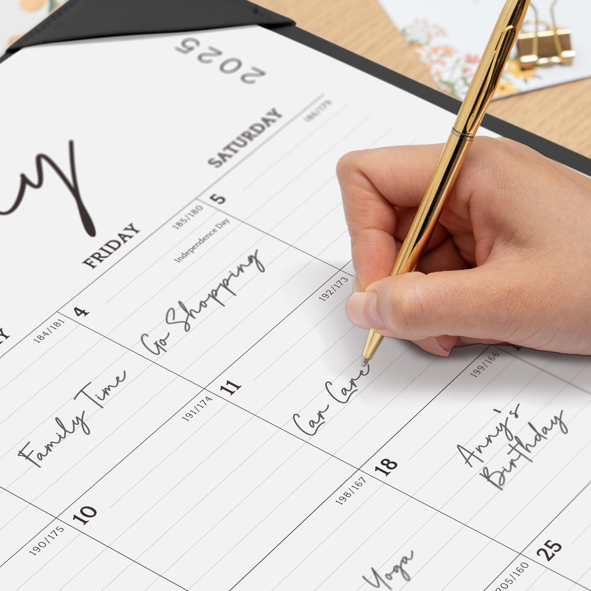 Hand holding a pen over a calendar with events written on it