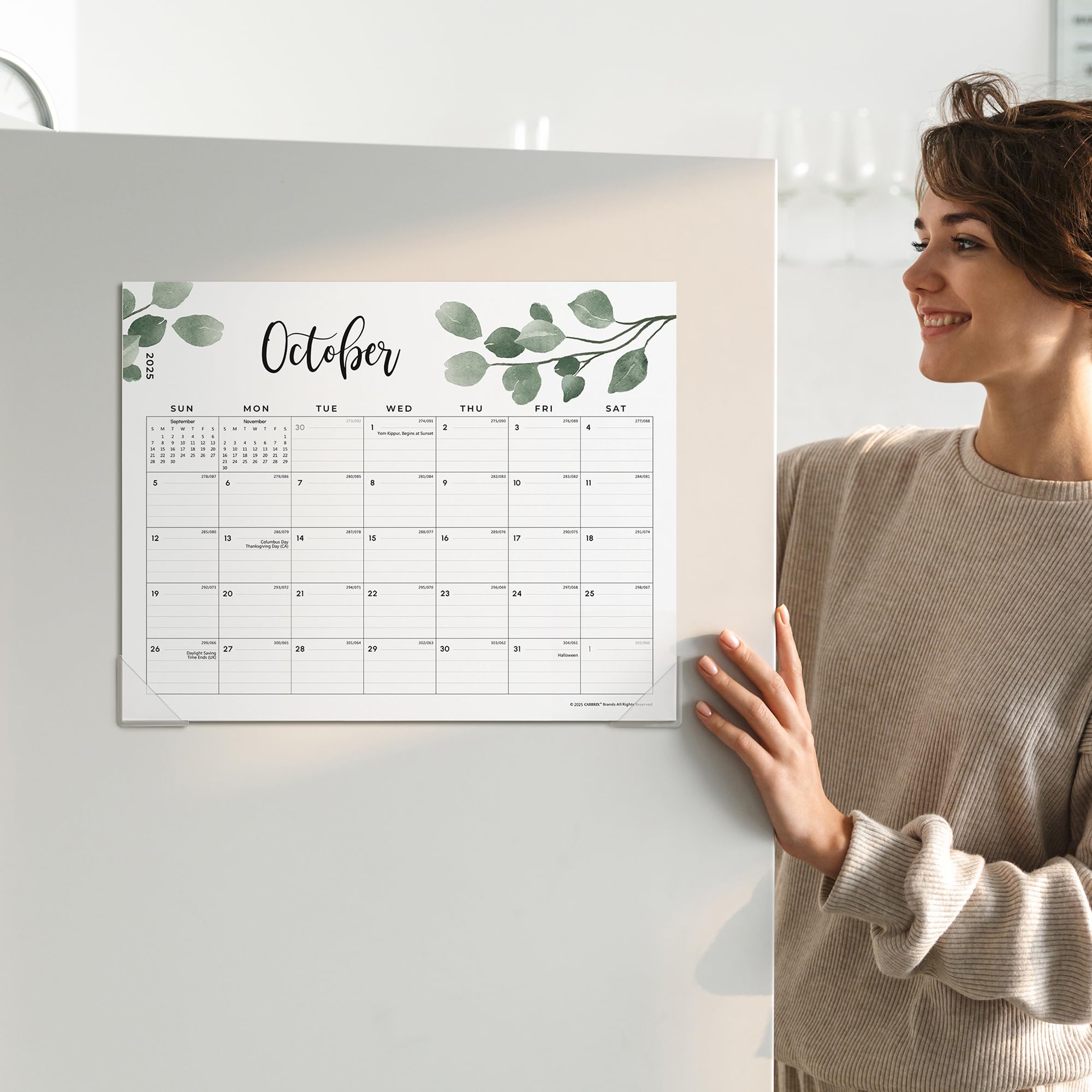 Woman holding a calendar with a leaf design on a white wall