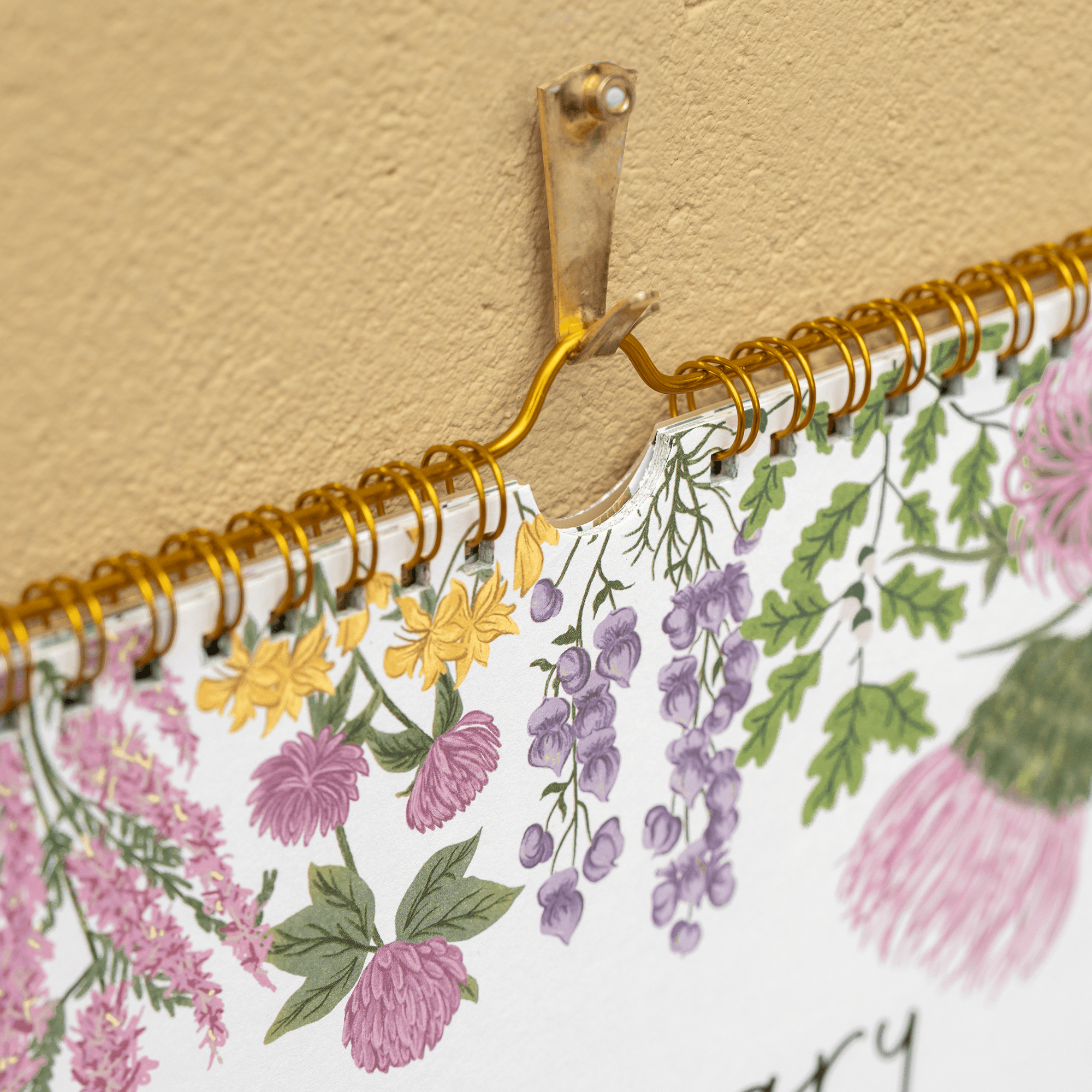 Floral-patterned notebook with gold spiral binding against a beige background