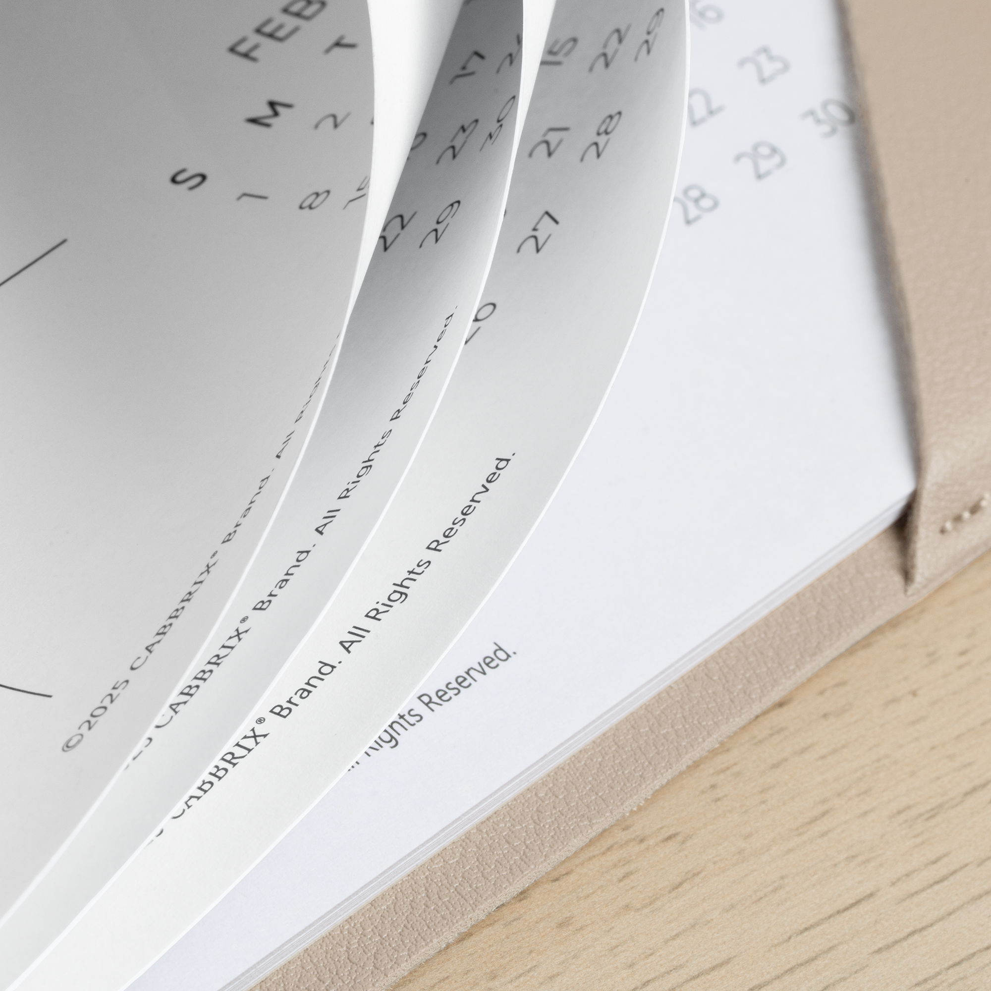 Calendar pages with a visible brand name on a wooden surface