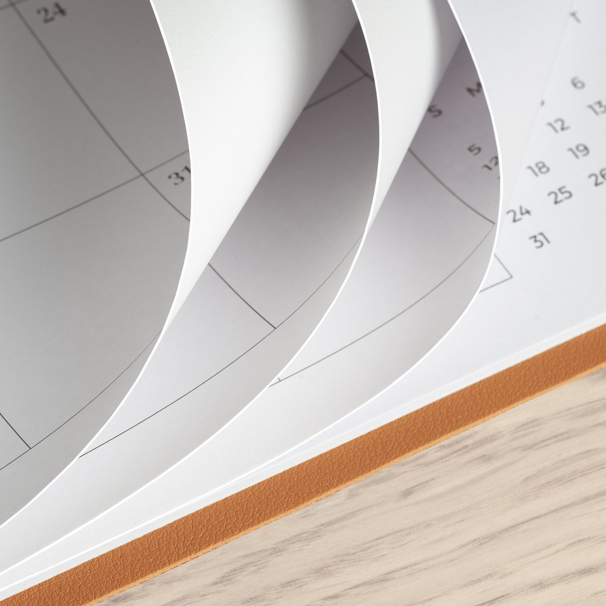 Close-up of a spiral-bound planner with pages curling outwards on a wooden surface.