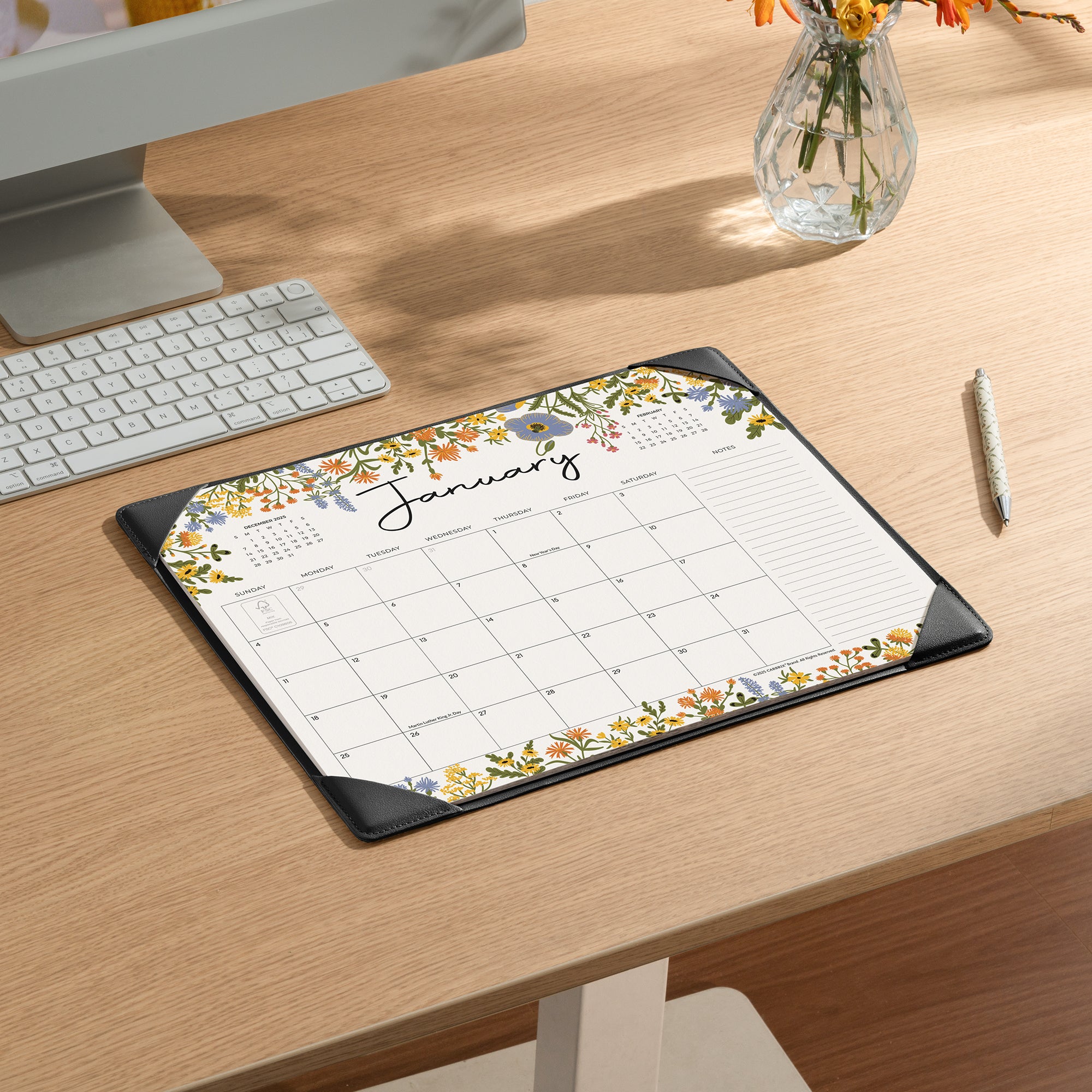 Floral calendar mat on a desk with a computer and keyboard.