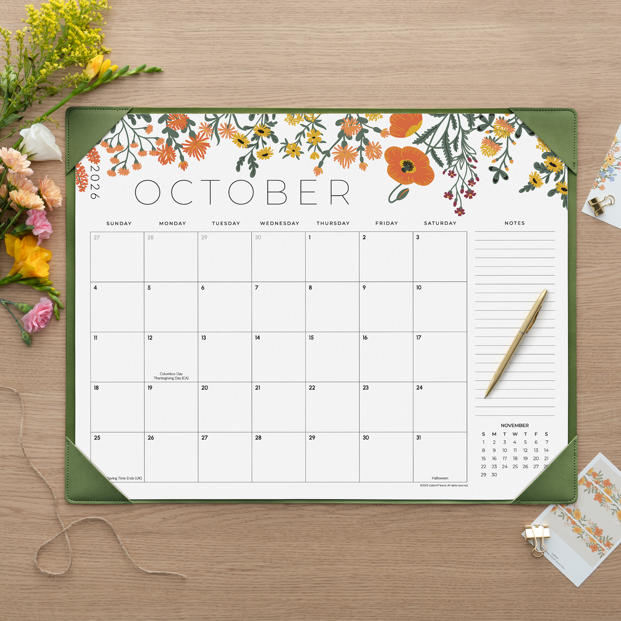Floral October calendar on a wooden surface with flowers and a pen.