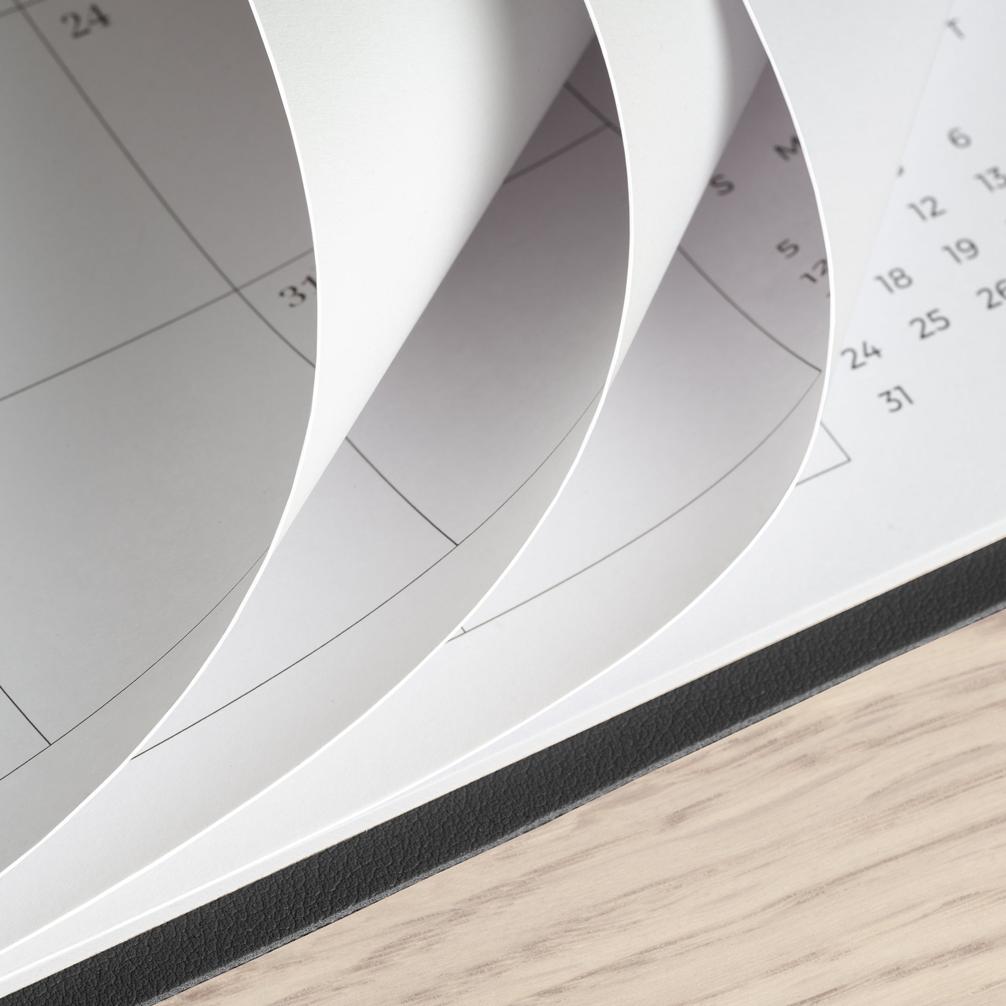 Close-up of a spiral-bound planner with pages curling outward on a wooden surface.