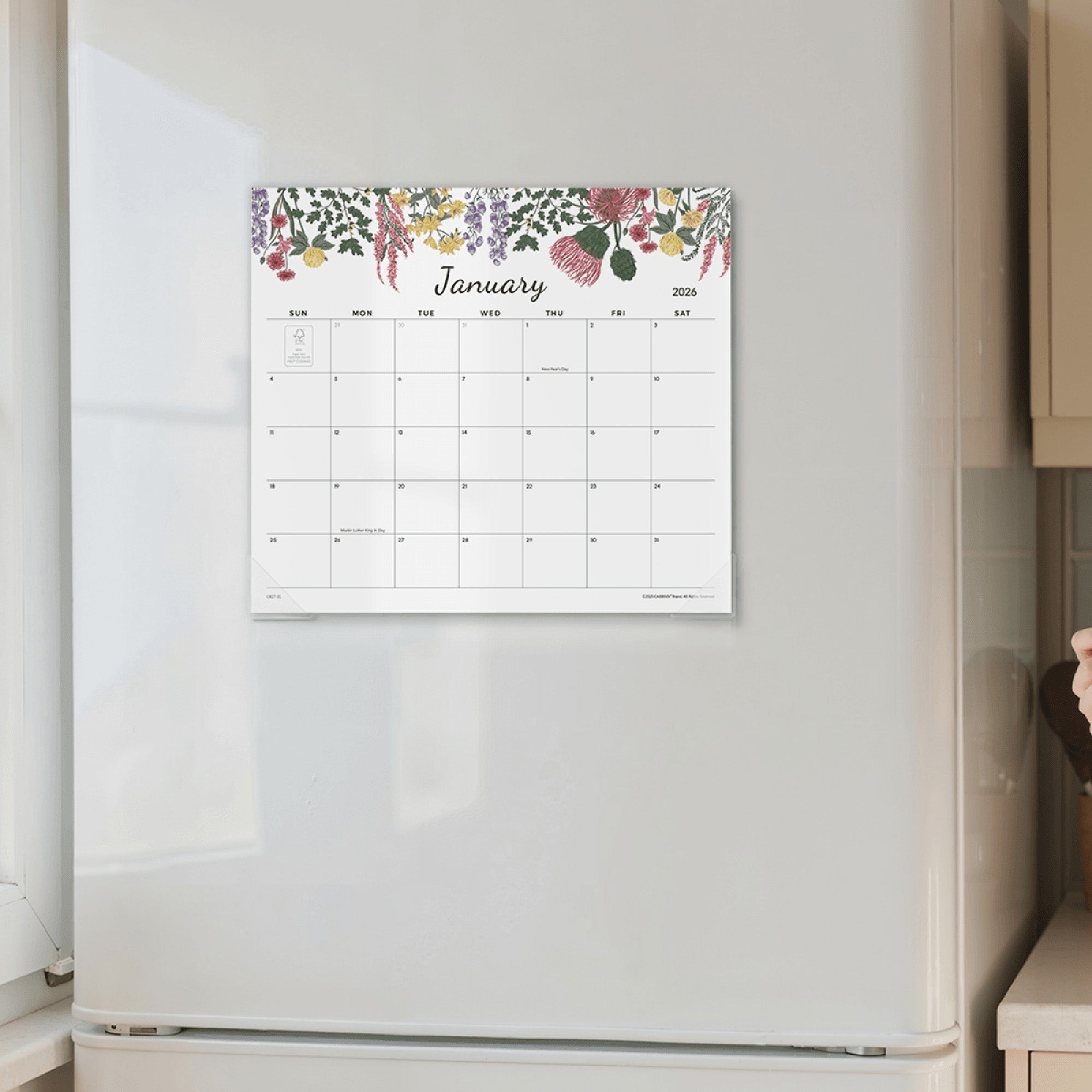 Floral-themed calendar on a wall above a refrigerator