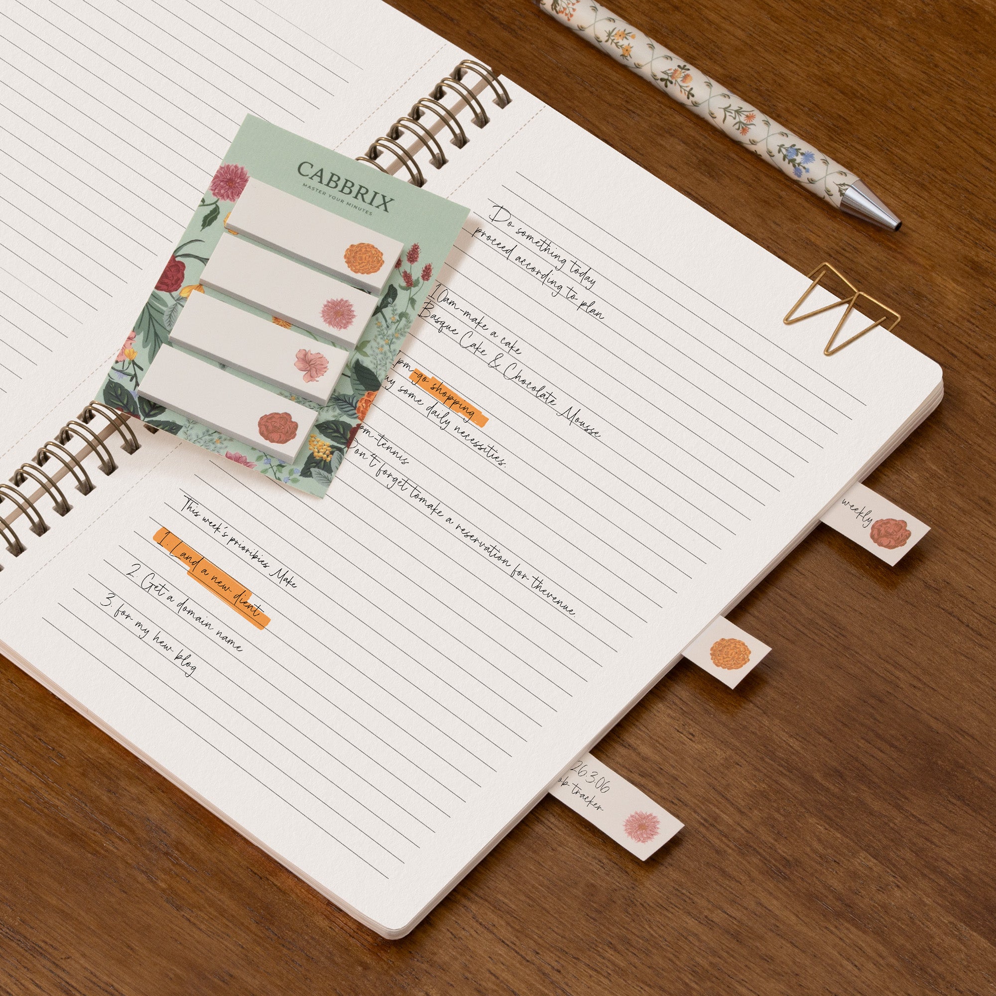 Notebook with planner stickers and a pen on a wooden surface