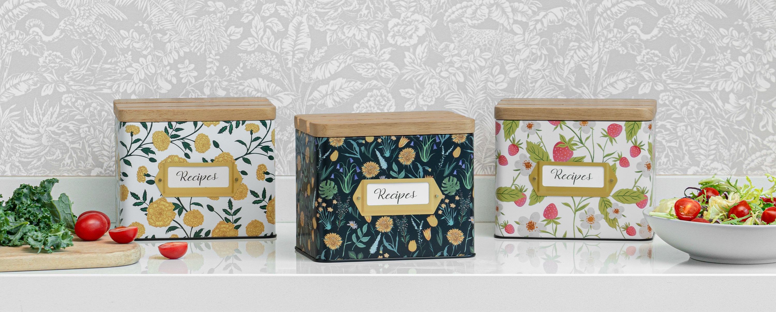 Three decorative kitchen canisters with floral patterns on a neutral background