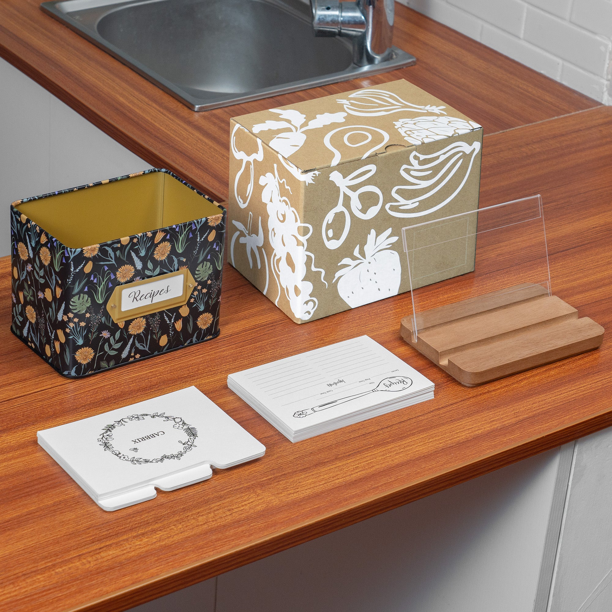 Decorative boxes and coasters on a kitchen counter with a sink in the background.