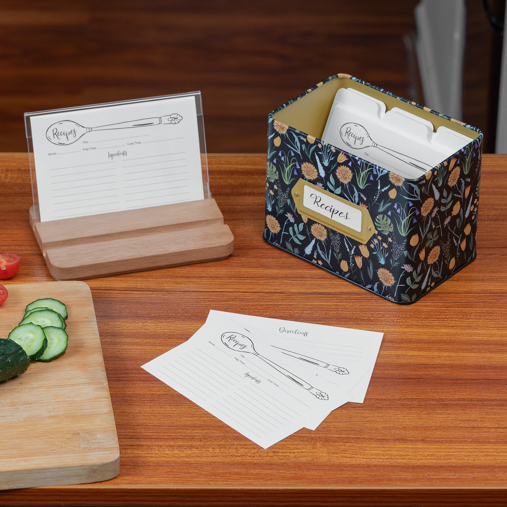 Kitchen scene with recipe cards, a wooden holder, and a patterned box on a wooden surface.
