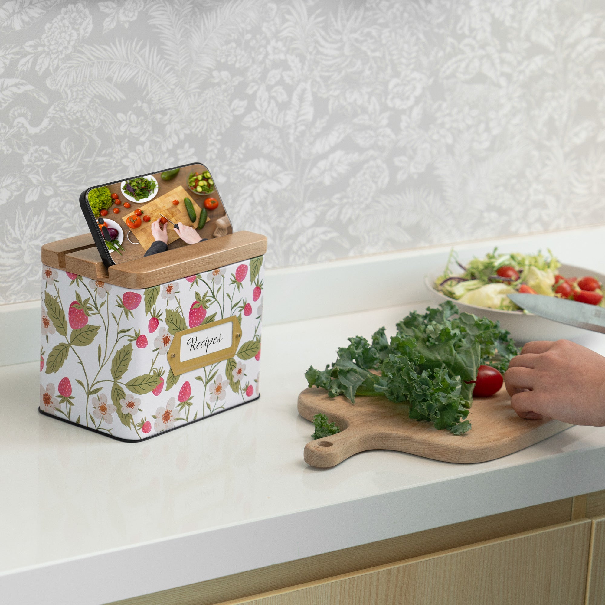 Kitchen counter with a floral-patterned canister, phone stand, and cutting board with vegetables.