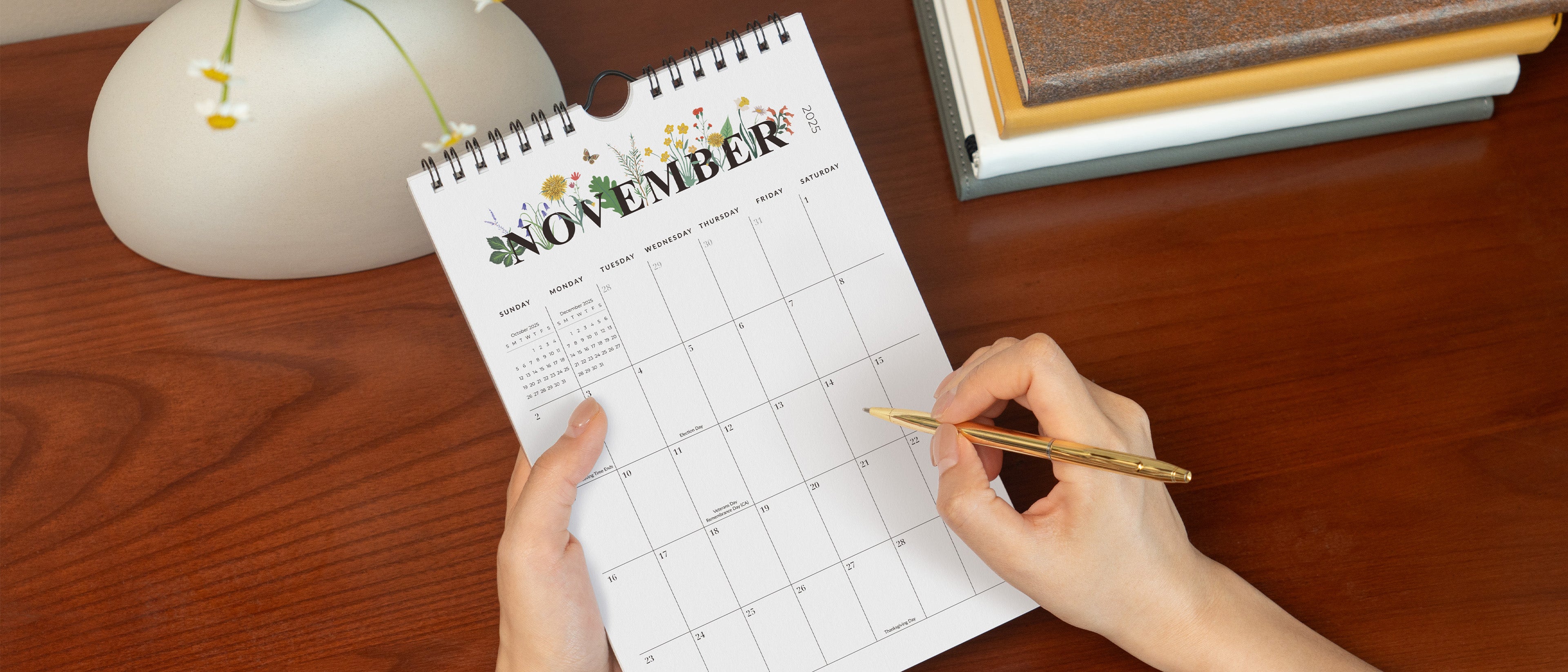 Person holding a pen and a November calendar on a wooden surface