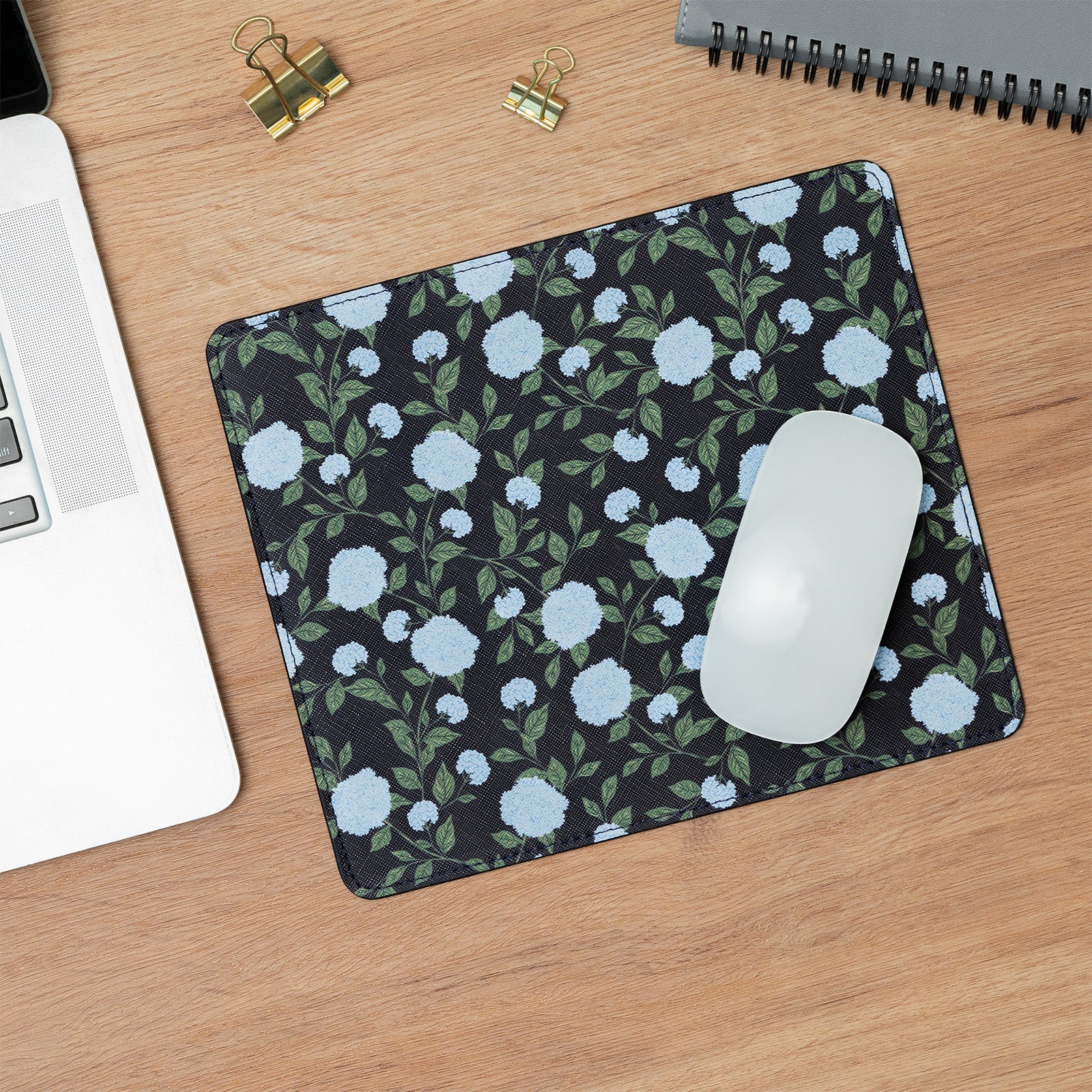 Floral mouse pad on a wooden desk with a laptop and mouse.