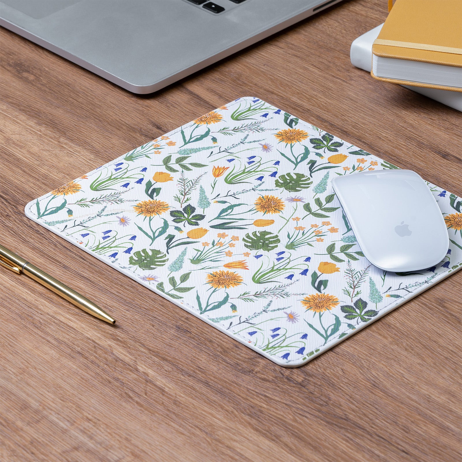 Floral mouse pad on a wooden desk with a laptop and mouse.
