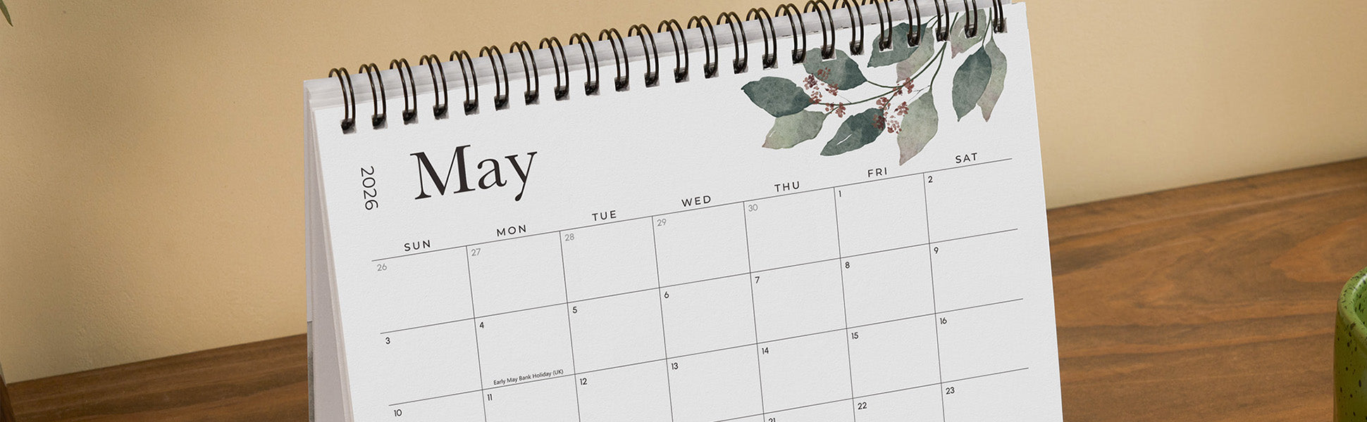 Calendar open to May on a wooden surface with a neutral background