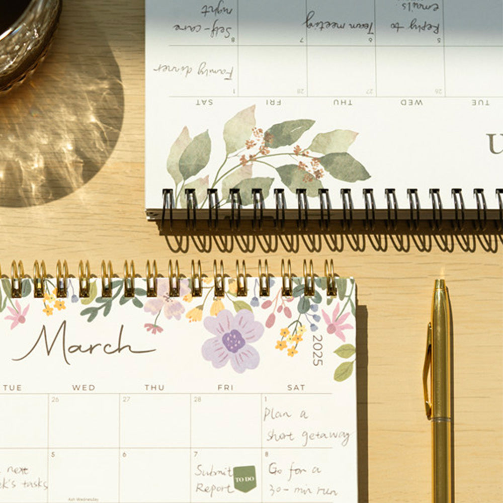 Calendar with floral design on a wooden surface with a pen