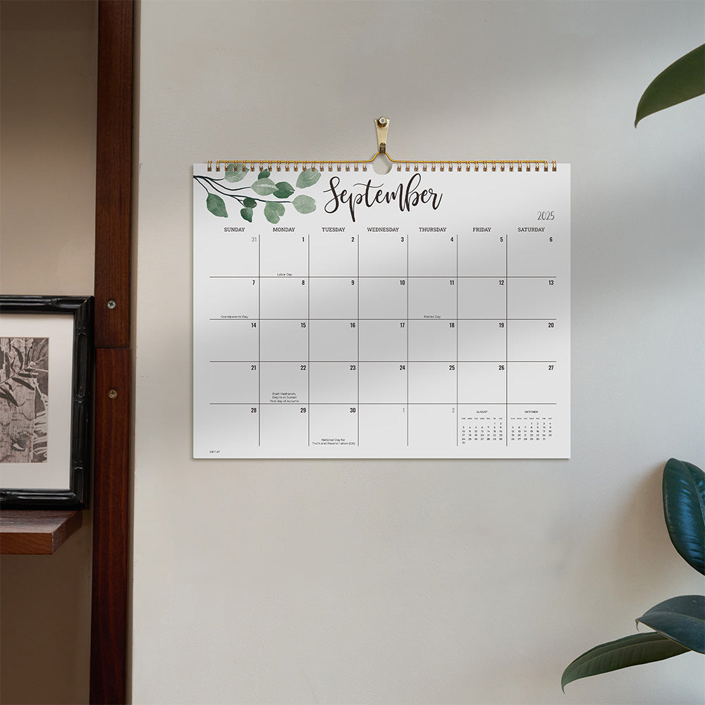 Wall calendar for September 2023 hanging on a white wall with decorative elements.