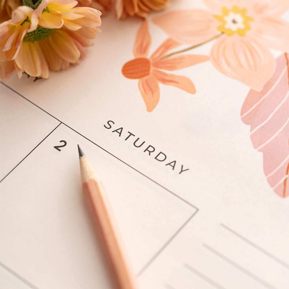 Calendar with flowers and a pencil on a white background