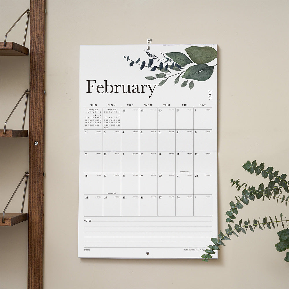 Calendar for February with green leaf design on a beige wall.