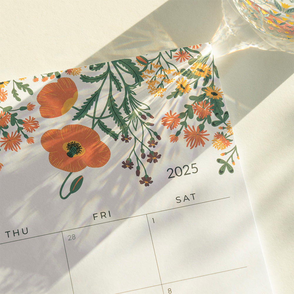 Calendar with floral design and '2025' printed on it, featuring orange flowers and green leaves.