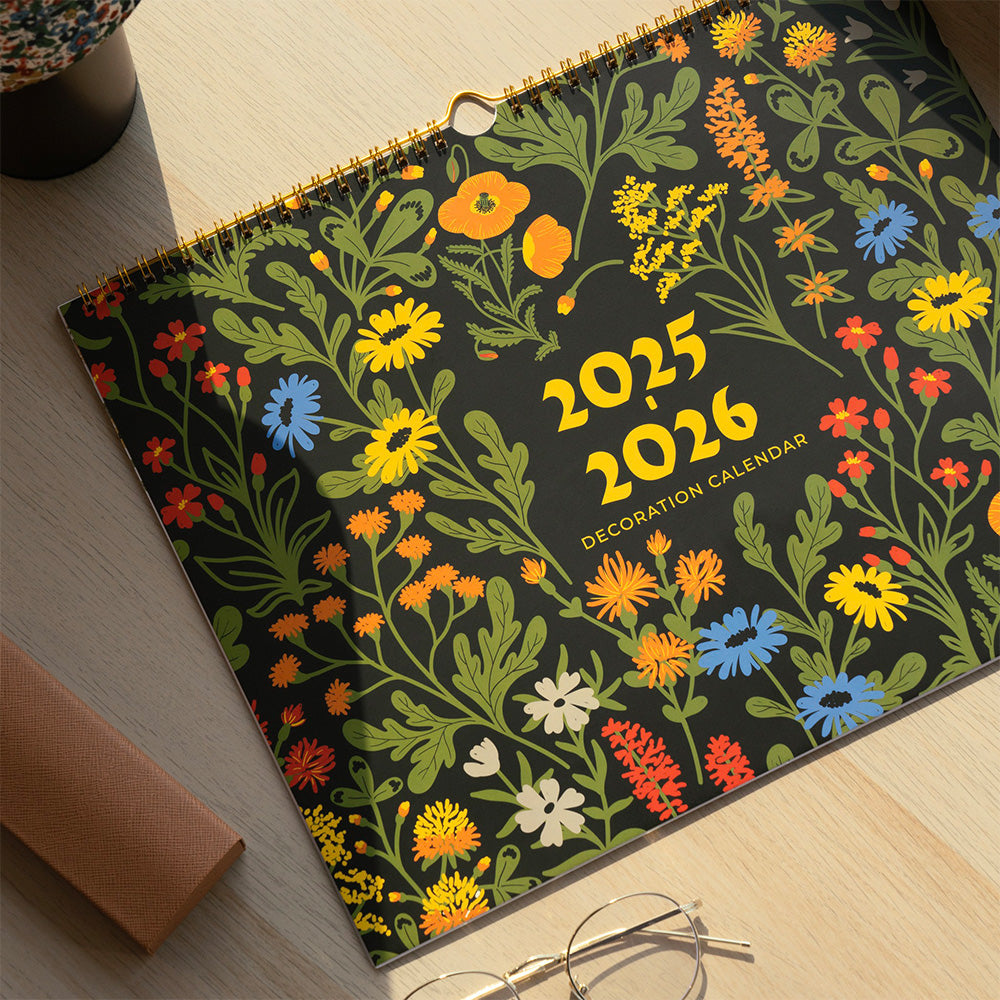 Floral design calendar for 2025-2026 on a wooden surface with glasses and a box.