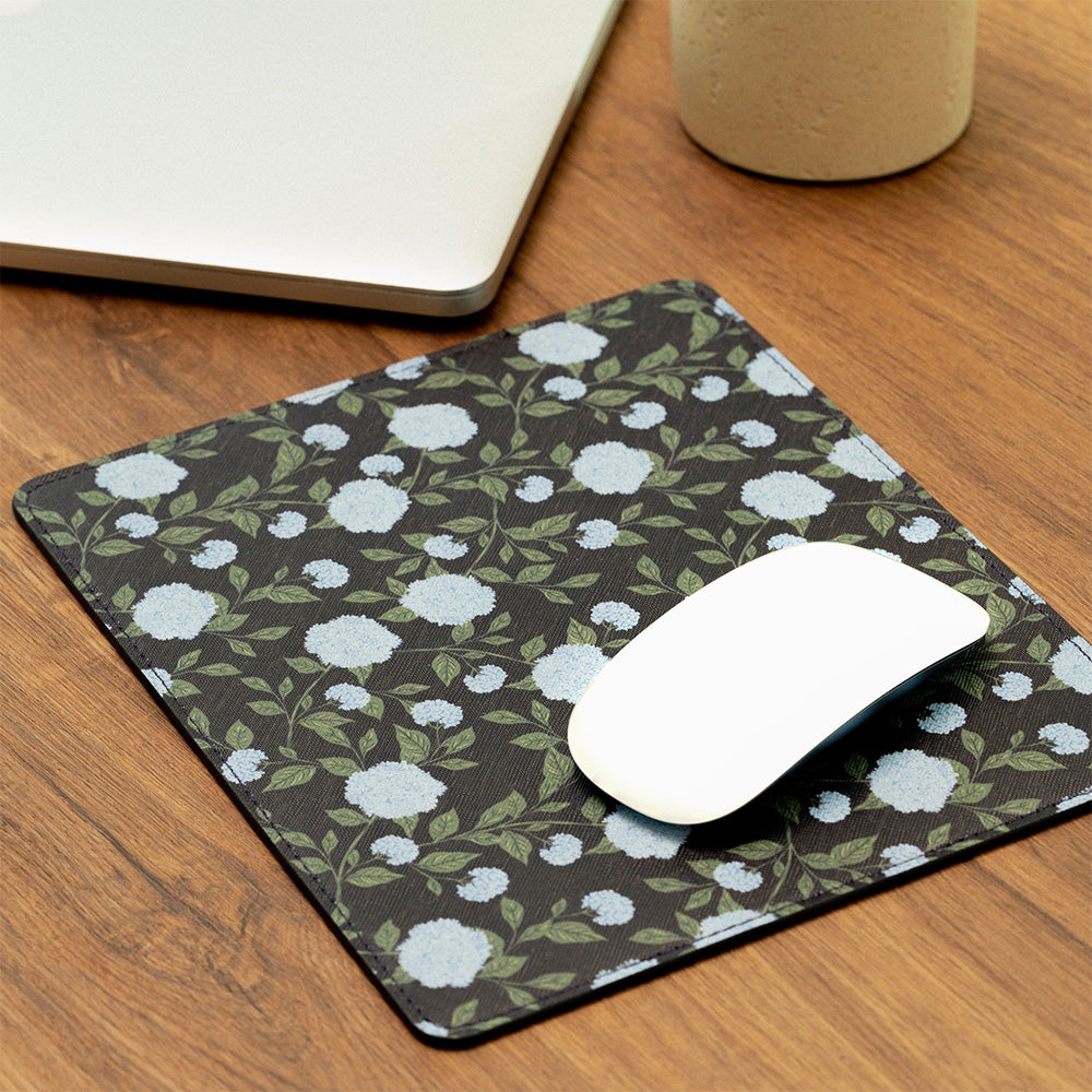 Floral patterned mouse pad on a wooden desk with a computer mouse.